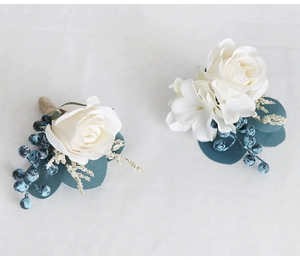 Detailed view of handmade white silk rose boutonniere with blue berries and burlap twine
