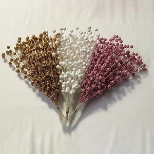 Flat lay of artificial berry stems with gold, white and pink glitter coating for holiday decor