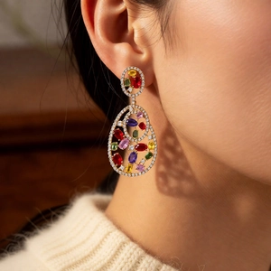 Close-up of vintage gold teardrop hollow earrings with multicolored gemstones on model