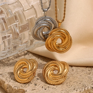 Close-up of twisted knot jewelry set with gold and silver necklaces on stone surface