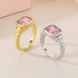 Detail of twisted titanium steel rings with rectangular pink zircon in gold and silver