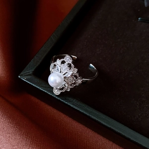 Macro detail of French zircon flower ring with pearl and adjustable silver band
