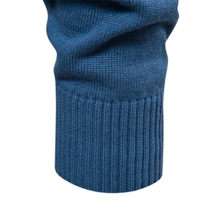 Detailed close-up of blue knit sweater cuff showing ribbed texture and high-quality yarn