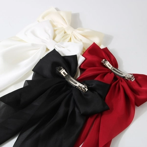 Detailed view of satin bow hair clips showing metal spring clips and handmade engraving