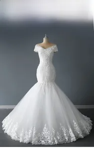 Détail de la robe de mariée en dentelle à épaules dénudées avec traîne sirène et broderie