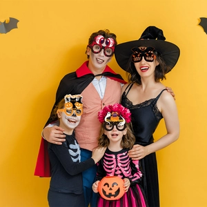 Familie mit lustigen Halloween-Brillen aus Papier mit Kürbis- und Fledermaus-Motiven