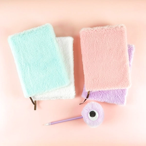 Dettaglio di quaderni in peluche colorati con una penna a sfera decorativa soffice