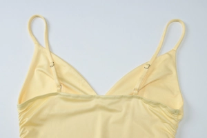 Detail of adjustable thin straps and metal buckle on yellow V-neck camisole dress