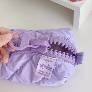 Purple quilted pen case with a large zipper and hisocute logo on a white desk
