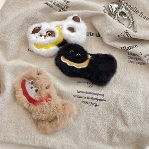 Detailed view of plush cartoon badges in white, black and brown with cute embroidery