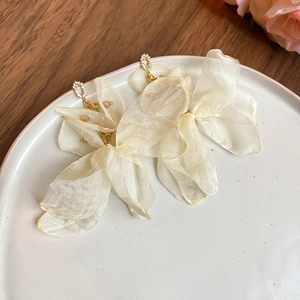 Detail shot of ivory chiffon flower tassel earrings with crystals on a ceramic tray