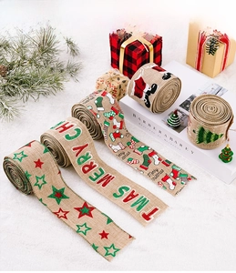 Detail view of four burlap Christmas ribbons with festive prints on soft white plush background