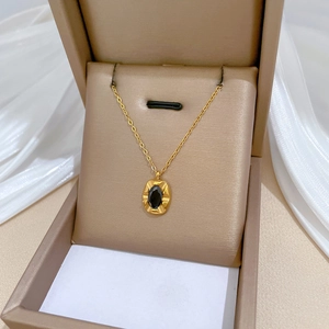 Minimalist gold titanium necklace with oval black gemstone pendant in jewelry box