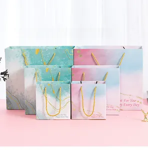 Trio of pink and marble gift bags with gold handles in small, medium, and large sizes