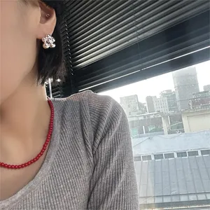 Primo piano di una modella con collana di perline rosse e orecchini a fiore in argento.
