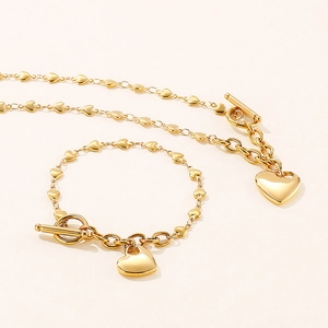 Golden heart link necklace and bracelet set with T-bar toggles on beige background