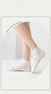 Detail of white thin cotton socks featuring ruffled lace edges and pink bow patterns