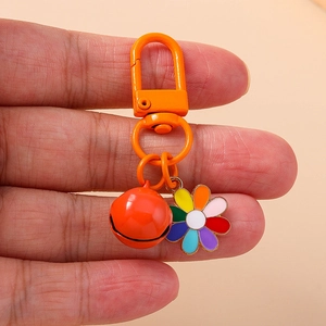 Handheld view of a vibrant colorful sunflower keychain with a bright orange metal bell