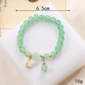 Détail d'un bracelet en perles colorées avec breloque papillon dorée et trèfle vert