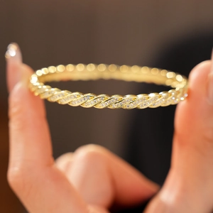 Detail of 18K gold twisted rope bracelet with micro-paved white zircons on a hand