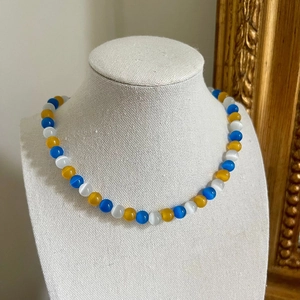 Detailed view of glacier blue cat eye stone beaded necklace with a heart pendant