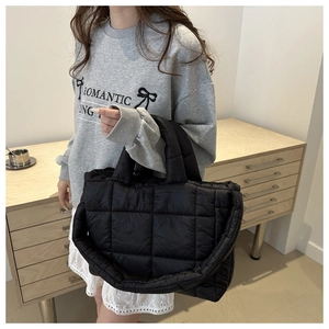 Detail of black quilted puffer tote bag showing soft texture and large capacity