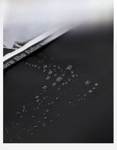 Close-up of waterproof high-density black nylon fabric with water droplets on a backpack