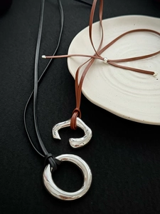 Close-up of minimalist mirror-finish silver pendant necklaces on leather cords