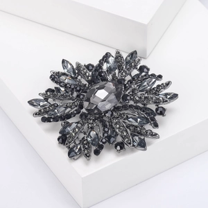 Übertriebene Retro-Blumenbrosche mit dunkelgrauen Kristallen auf weißen Blöcken