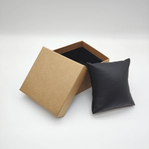 Detail view of square kraft paper gift box with a soft black leather watch cushion inside