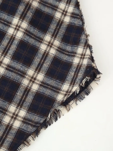 Detail of blue and brown plaid fabric with frayed fringe edges on a summer dress
