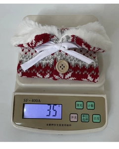 Detail of red and white knit wine bottle cover with faux fur collar and wooden button