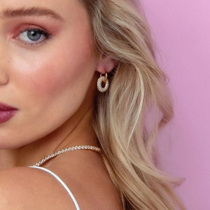 Close-up of a model wearing 18k gold plated pavé crystal hoop earrings and necklace set