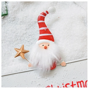 Detail view of a gnome Christmas ornament with red striped hat and golden star