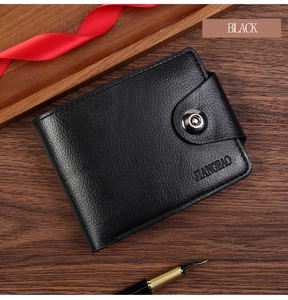 Close-up of black litchi grain leather wallet with metal snap button on wooden desk