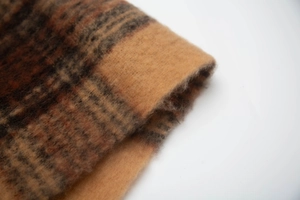 Macro close-up showing the thick, brushed texture of the brown plaid scarf fabric