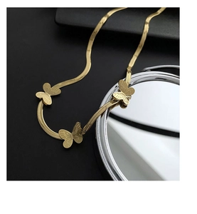 Détail macro de pendentifs papillon dorés sur une chaîne serpent avec effet de miroir