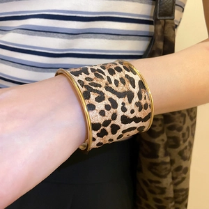 Close-up of wide leopard print bangle with gold trim worn by a model in a trendy style