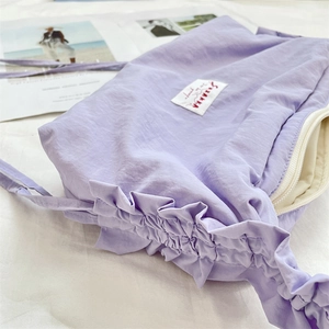 Dettaglio della borsa in nylon plissettato lavanda con etichetta e cerniera bianca