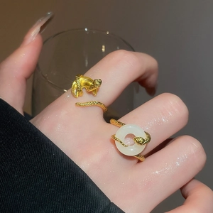 Macro detail of gold snake-shaped rings with yellow rectangular zircon and white stone inlay