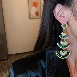 Close-up of emerald green layered fan earrings with crystal tassels on female model
