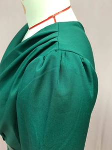 Detailed view of the V-neckline and puffed shoulder sleeves on the green sequin shirt