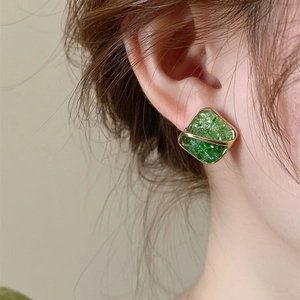 Close-up of a green square stud earring with ice-cracked texture on a model's ear