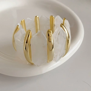 Gros plan de perles en acrylique et segments en métal doré sur un bracelet élastique