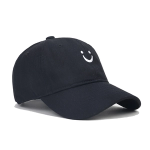 Close-up of the white embroidered smiley face detail on a black cotton baseball cap