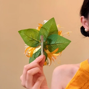 Detailed back view of a yellow fabric flower hair clip with a metal duckbill attachment