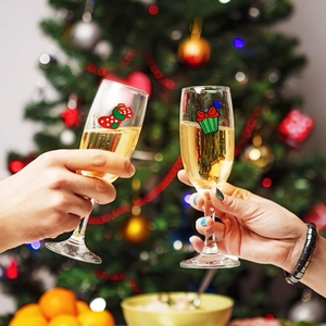 Close-up of Christmas wine glass markers featuring red socks and green gift box charms