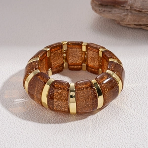 Detailed view of amber acrylic bracelet with gold glitter and metallic link connectors
