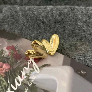 Macro detail of gold heart-shaped earrings with hand-hammered textured metal finish