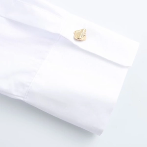 White commute blouse with long sleeves featuring a detailed golden metal button cuff